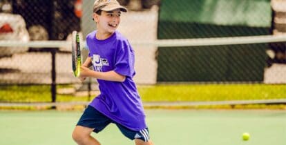Boy smiling and playing tennis