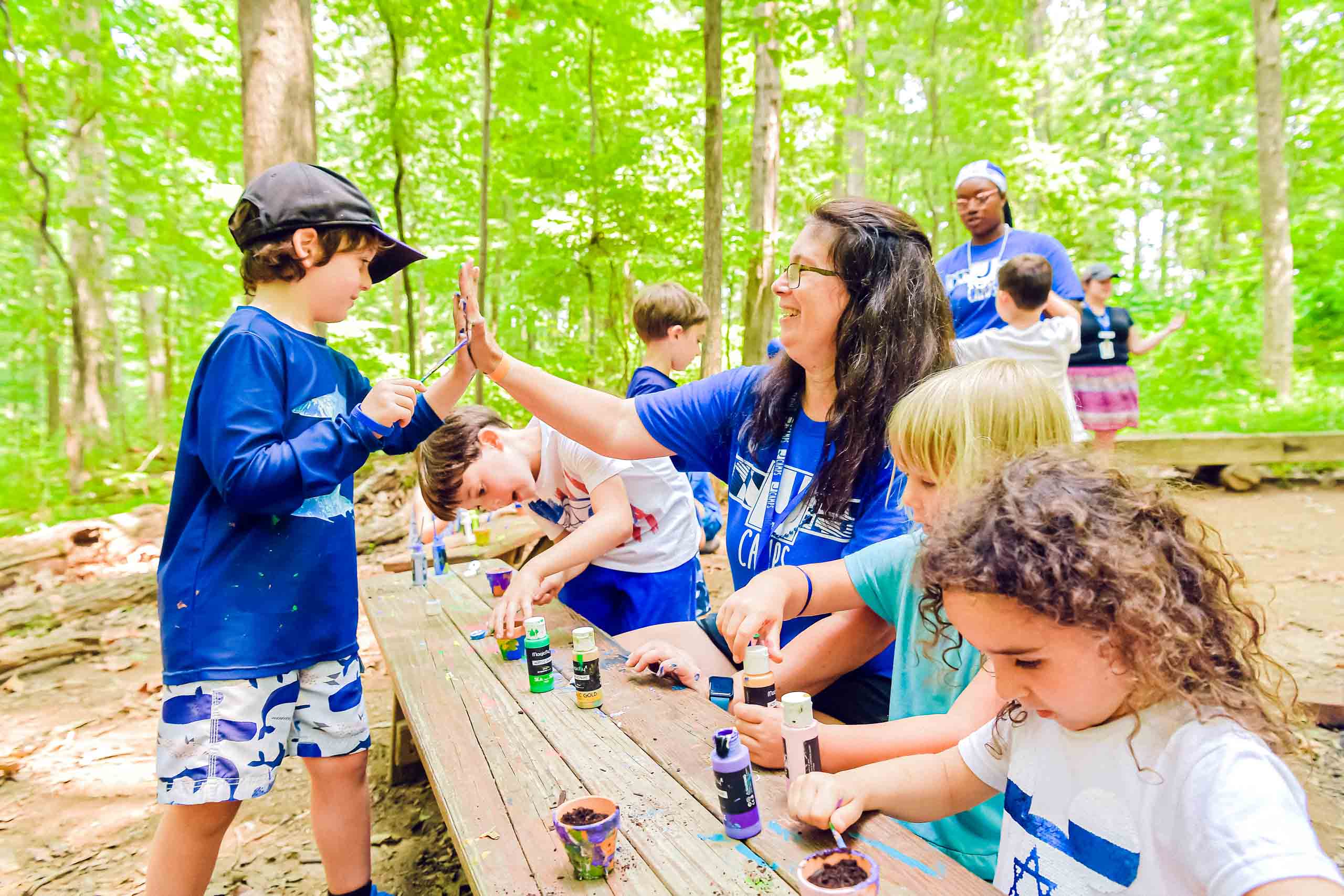 Campers doing crafts in the woods.